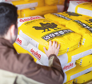 deuka employees in front of a pallet with poultry feed