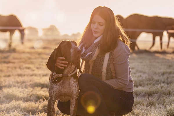 Young woman stroking dog in the dawn