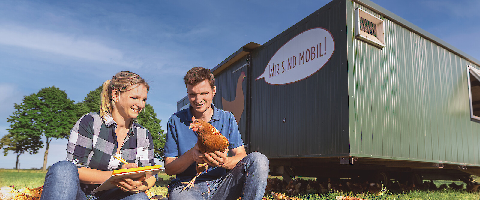 Landwirt und Geflügelfachberaterin diskutieren optimales Management der Legehennen vor dem Mobilstall (© deuka Tiernahrung Cremer).