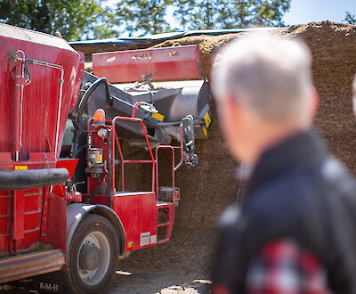 Farmer and deuka advisor watching agricultural machine removing maize silage (© Deutsche Tiernahrung Cremer).