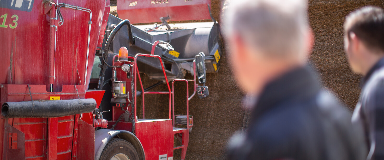 Farmer and deuka advisor watching agricultural machine removing maize silage (© Deutsche Tiernahrung Cremer).