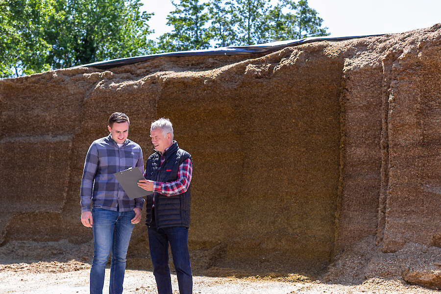 Farmer and deuka advisor stand in front of maize silo and discuss the optimal ration design based on high quality maize silage (© Deutsche Tiernahrung Cremer).