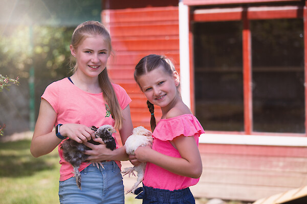 Freundinnen mit Hühnern vor Gartenhütte